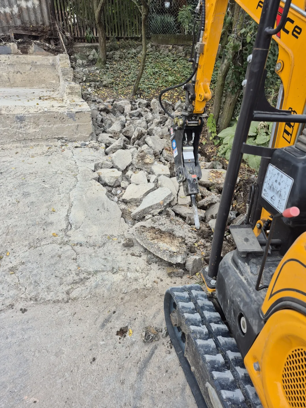 Hidraulikus bontókalapács betonlapot bont, körülötte feltört betontörmelék