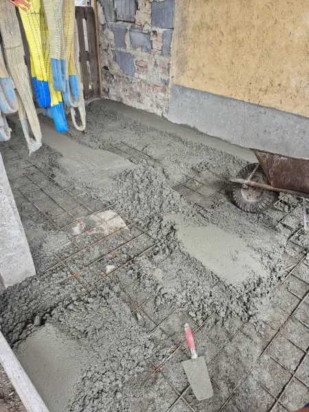 A beton bedolgozása a kőlábazat mellett.