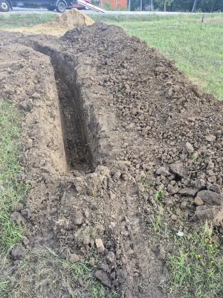 A kiásott árok a füves telken.