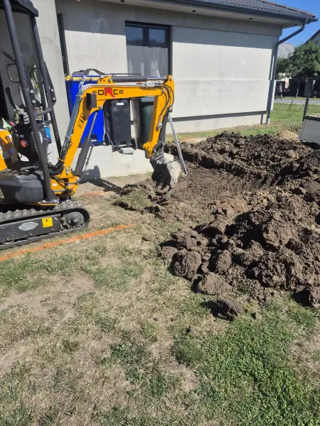 A kotró megkezdi az árok kiemelését a ház mellett.