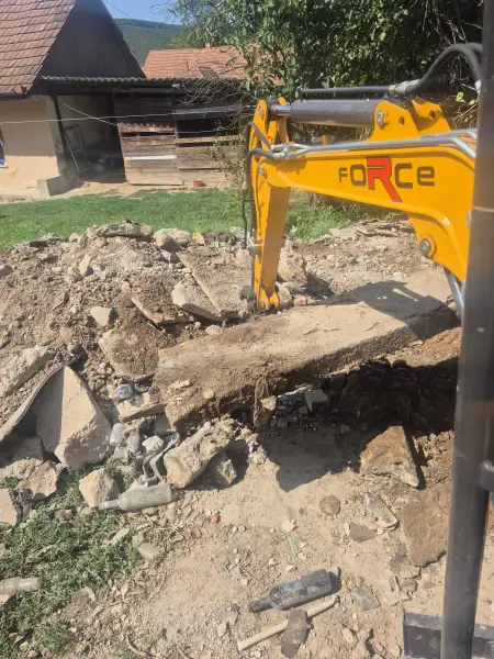 A régi betontábla bontása kotrókanállal.