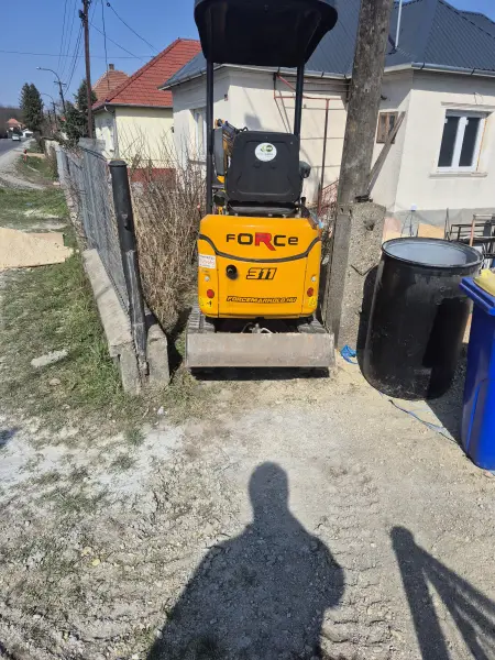 A minikotró szűk helyen, a meglévő kerítés mellett.