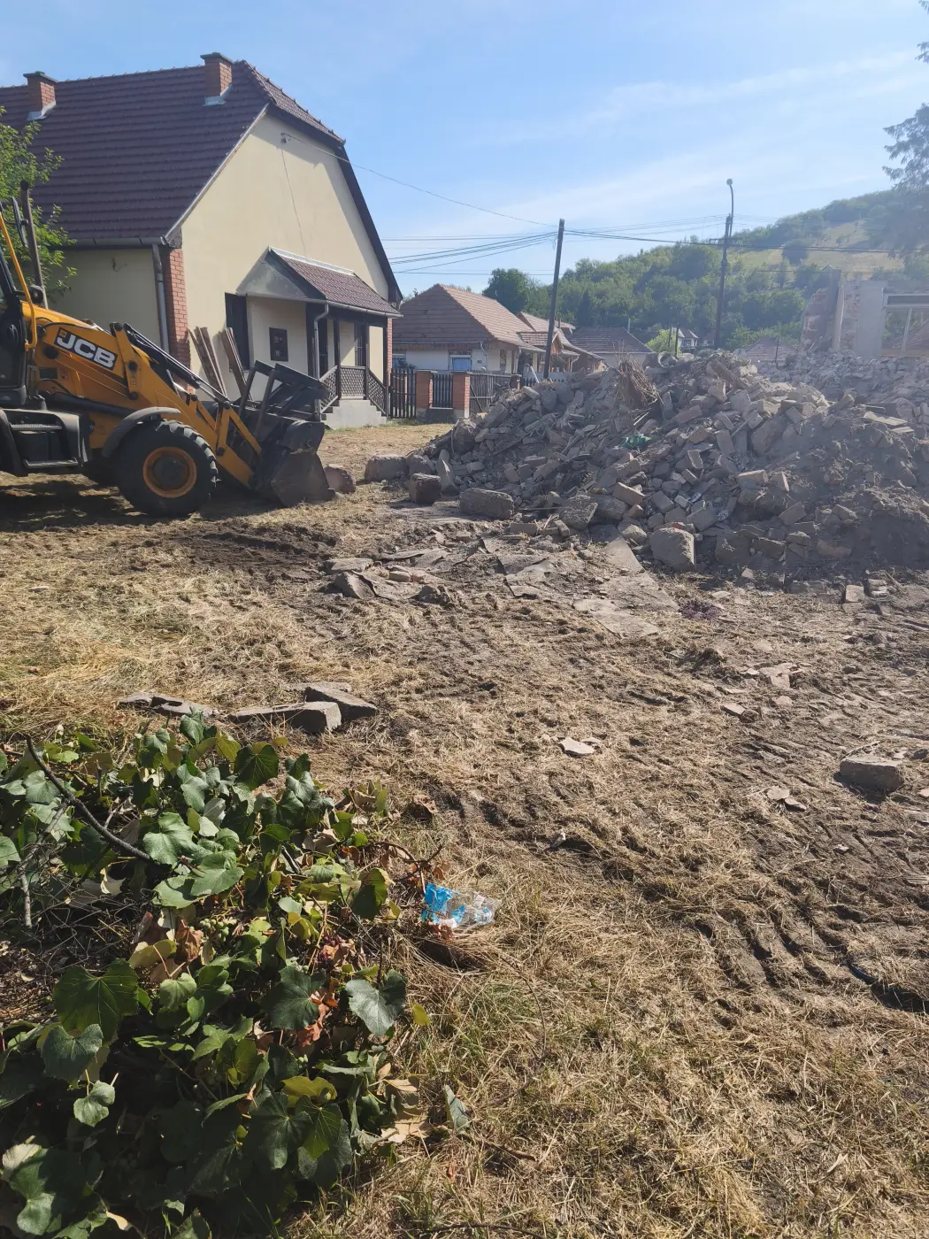 Homlokrakodó rakja a tégla- és betontörmeléket, a ház közvetlen közelében.