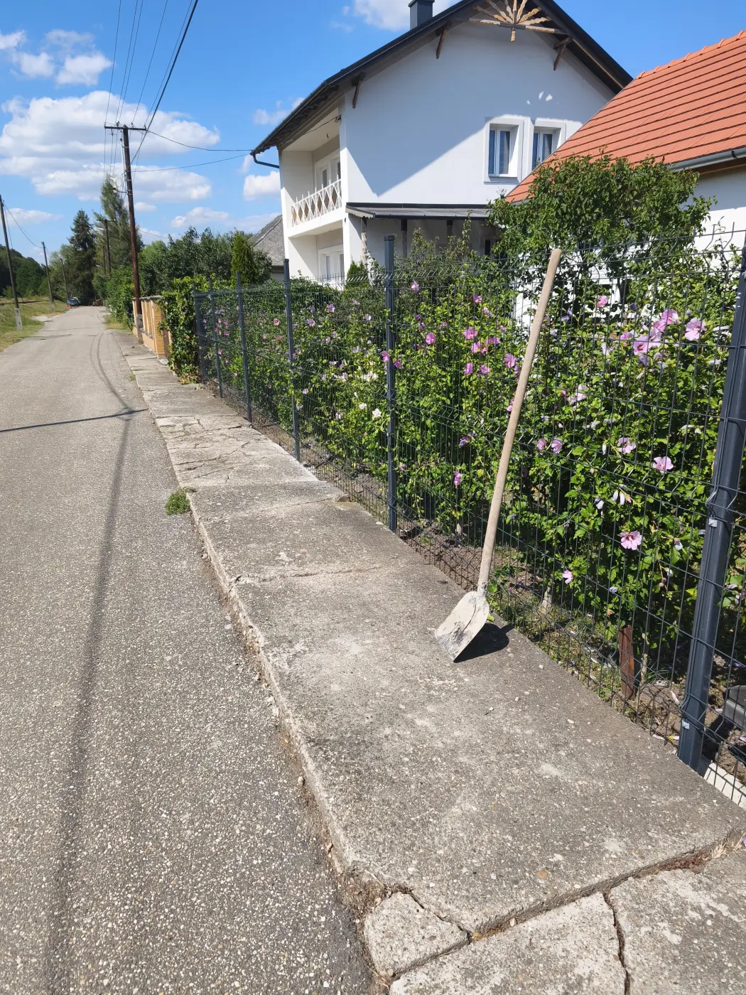A kész kerítés a járda mellett – az oszlopsor a burkolat vonalát követi.